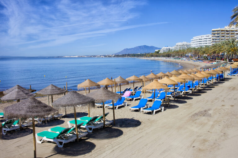 Sun,Loungers,And,Straw,Shade,Umbrellas,On,A,Beach,By